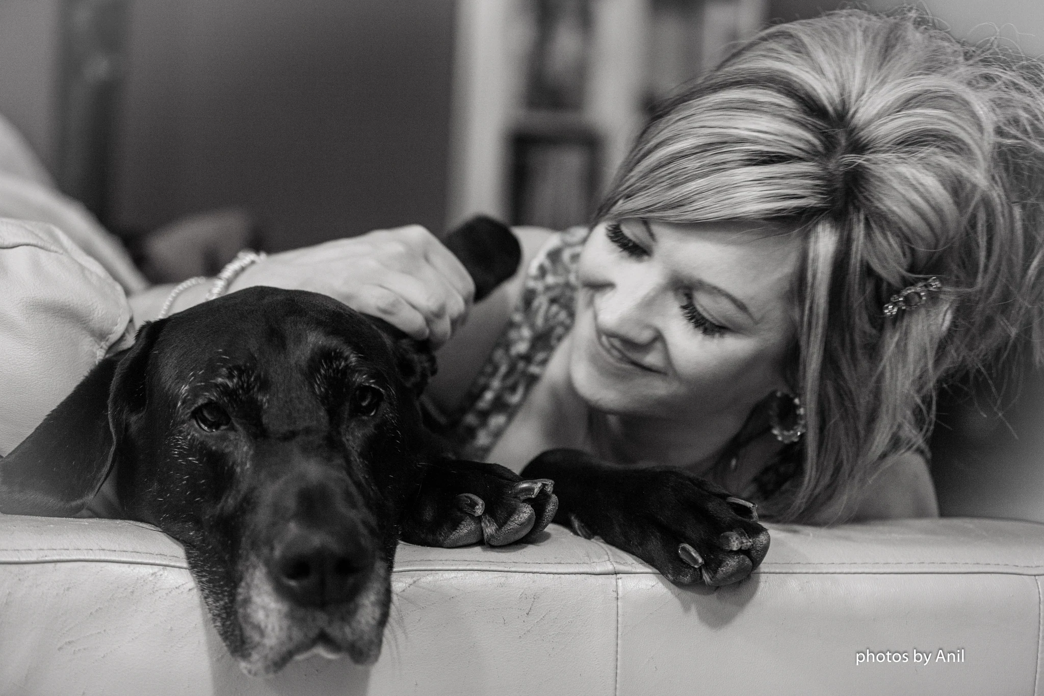 A woman lying nose to nose with a Great Dane on a sofa, in black and white